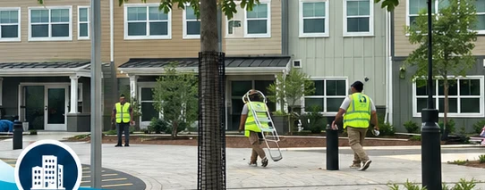 10dow Clean crew members in high-visibility vests carrying equipment along a newly built townhome development